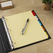 A pen on a Avery 5-tab divider set in a binder.