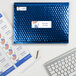A blue envelope with a white Avery mailing label next to a keyboard and a pen.