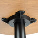 A black metal pole with a round wood surface on a bar height table.
