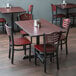 A Lancaster Table & Seating dining set with mahogany chairs and a cherry table with black legs.