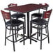 A Lancaster Table & Seating bar height table with a reversible cherry and black top and four mahogany bistro chairs with padded seats.