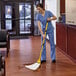 A woman in scrubs uses a yellow Rubbermaid biohazard mop pad to clean the floor in a hospital.