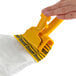 A hand holding a yellow Rubbermaid Biohazard Mop Pad.