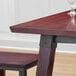 A Lancaster Table & Seating solid wood dining table with a wine glass on it.
