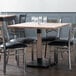A Lancaster Table & Seating square dining table with a wooden top and antique white wash finish.