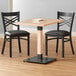 A Lancaster Table & Seating live edge dining table with two black chairs.