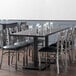 A Lancaster Table & Seating solid wood dining table with chairs around it in a restaurant dining area.