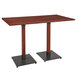 A Lancaster Table & Seating live edge bar height table with a mahogany finish and two black legs.