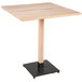 A Lancaster Table & Seating square wooden table with a black base.