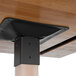 A black metal support plate on the corner of a Lancaster Table & Seating wood bar height table.