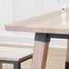 A Lancaster Table & Seating live edge bar height table with a glass of wine on it.