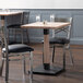 A Lancaster Table & Seating dining table with two chairs in a restaurant dining area.