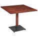 A Lancaster Table & Seating square wood table with a mahogany top and black metal base.