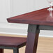 A Lancaster Table & Seating solid wood table with a wine glass on it.