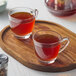 A wooden tray with two glass cups of Numi Organic Rooibos Chai Tea.