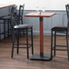 A Lancaster Table & Seating wooden bar height table base on a table with chairs around it.