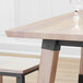A Lancaster Table & Seating square wooden dining table with a glass on it.