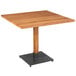 A Lancaster Table & Seating square wooden dining table with a metal base.