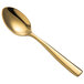 A close-up of a Bon Chef gold stainless steel demitasse spoon with a long handle.