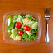 A Dart clear rectangular plastic container filled with a salad with tomatoes, lettuce, and croutons.