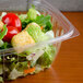 A Dart clear plastic rectangular container filled with salad, tomatoes, lettuce, and croutons.