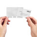 A person's hands holding clear business card sleeves with business cards inside.