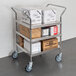 A Regency stainless steel three shelf utility cart with boxes on it.