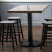 A Lancaster Table & Seating black cast iron counter height table base with stools.