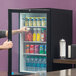 A person opening a Beverage-Air countertop display refrigerator with drinks.