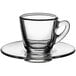 An Acopa clear glass espresso cup and saucer set.