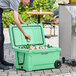 A man putting a can into a CaterGator seafoam outdoor cooler.
