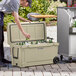 A man opening a CaterGator outdoor cooler filled with beer bottles at a table.