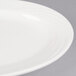 A close-up of a CAC Garden State bone white oval platter with a wavy rim.