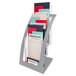 A silver Deflecto 3-tier literature holder with several magazines.