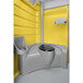 A PolyJohn portable restroom with a yellow exterior and a white toilet seat and sink.