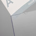 A white and grey paper with a blue letter a in a Deflecto clear slanted sign holder.