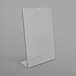 A clear plastic Deflecto slanted sign holder on a white surface.