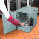 A person wearing gloves opening a Cambro slate blue insulated food pan carrier.