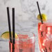 Two glasses of pink liquid with EcoChoice black paper straws on a table.