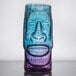 A blue and purple Moai tiki glass with a carved face on it.