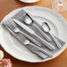 A white plate with Acopa Harmony stainless steel flatware on it.