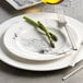 A white Reserve by Libbey porcelain plate with a fork and a piece of asparagus on it.