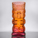 A Warrior lava red tiki glass with a face on it.