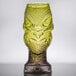 A close up of a green Head Hunter Tiki glass with a yellow design on it.