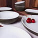 A white rectangular Elite Global Solutions Kona platter with chocolate speckles on a table with bowls of cherries.