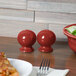 A table set with Fiesta Scarlet China salt and pepper shakers, a bowl, and a plate of pizza.