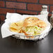 An American Metalcraft stainless steel wire basket with a croissant sandwich and chips.