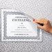 A hand using C-Line Cubicle Keepers to display a paper certificate.