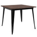 A Flash Furniture square dining table with a black metal base and rustic walnut wood top.