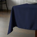 A table with a navy blue Intedge square tablecloth on it.